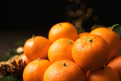 Photo of Fresh tangerines with fir tree branches on table, closeup. Christmas atmosphere