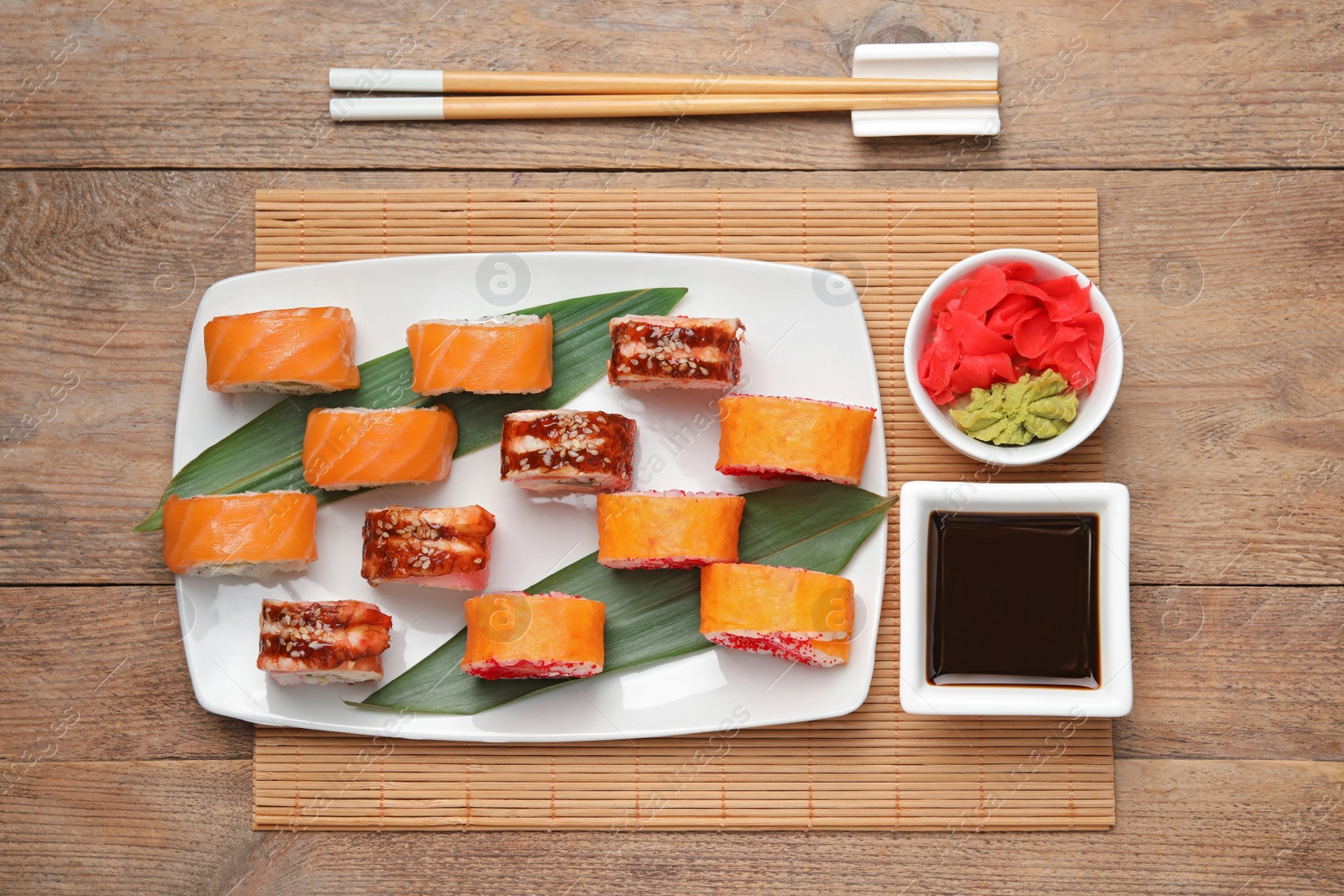 Photo of Flat lay composition with delicious sushi rolls on wooden table