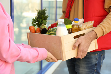 Photo of Woman receiving fresh products from courier outdoors, closeup. Food delivery service