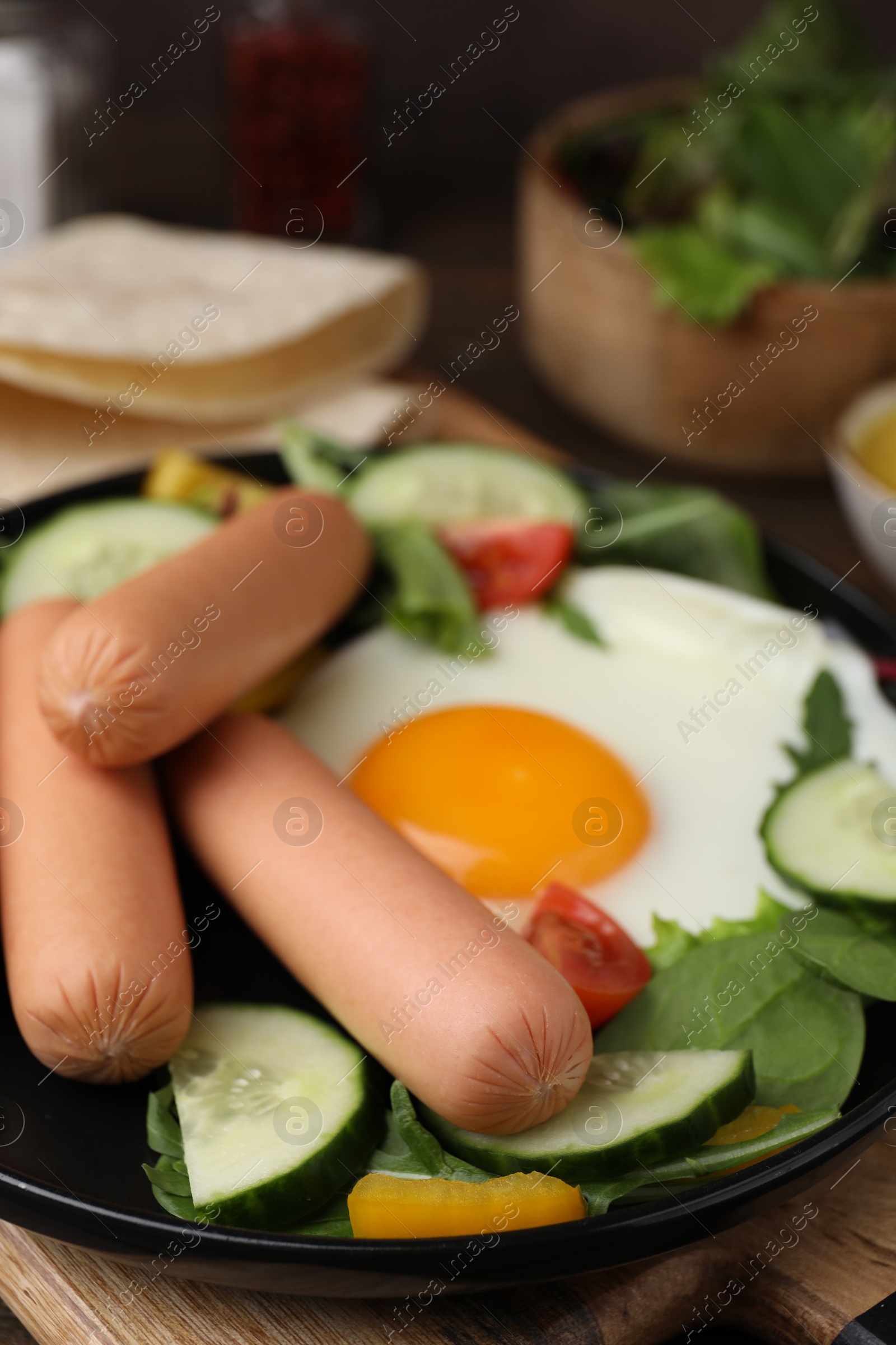 Photo of Delicious breakfast with boiled sausages and fried egg on wooden table, closeup