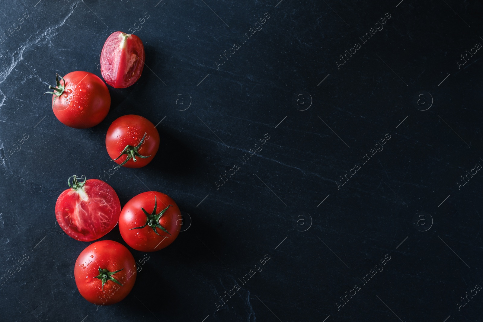 Photo of Fresh ripe tomatoes on black table, flat lay. Space for text