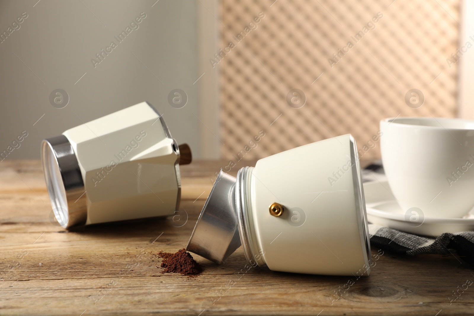 Photo of Moka pot and ground coffee on wooden table indoors