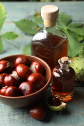 Photo of Chestnuts, leaves and bottles of essential oil on blue wooden table
