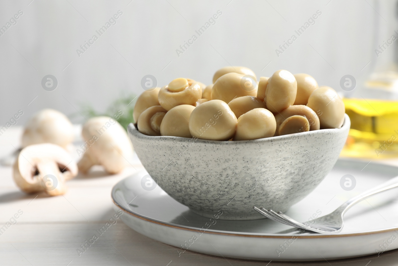 Photo of Delicious marinated mushrooms in bowl on white table