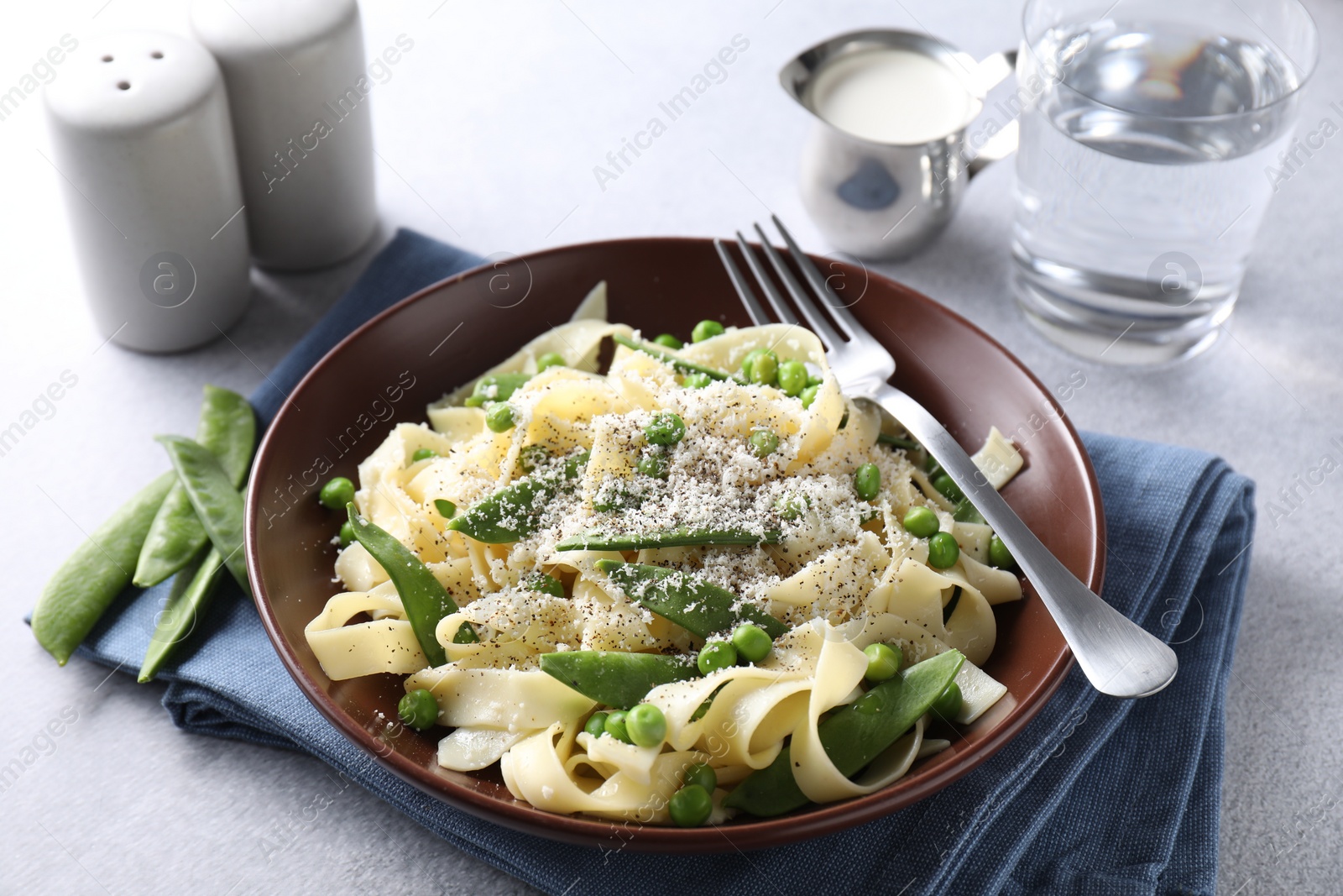 Photo of Delicious pasta with green peas and cheese served on grey table