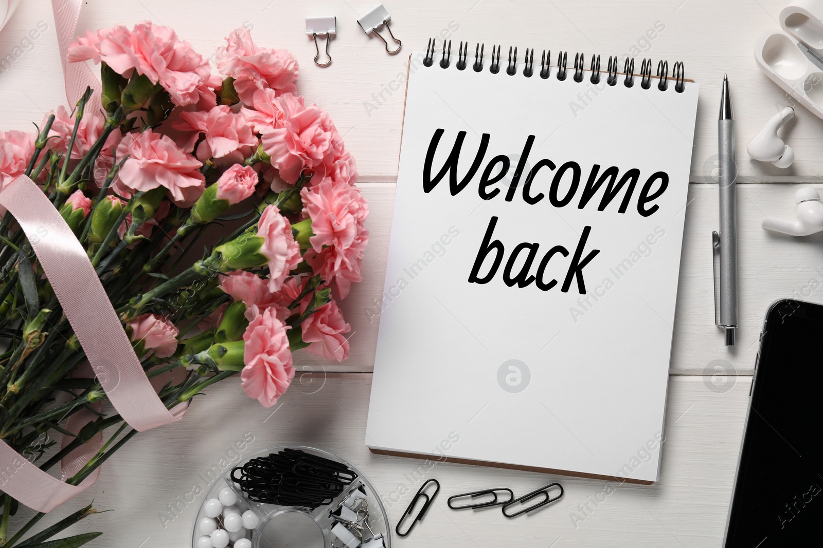 Image of Notebook with phrase Welcome Back, bouquet of flowers and stationery on white wooden table, flat lay