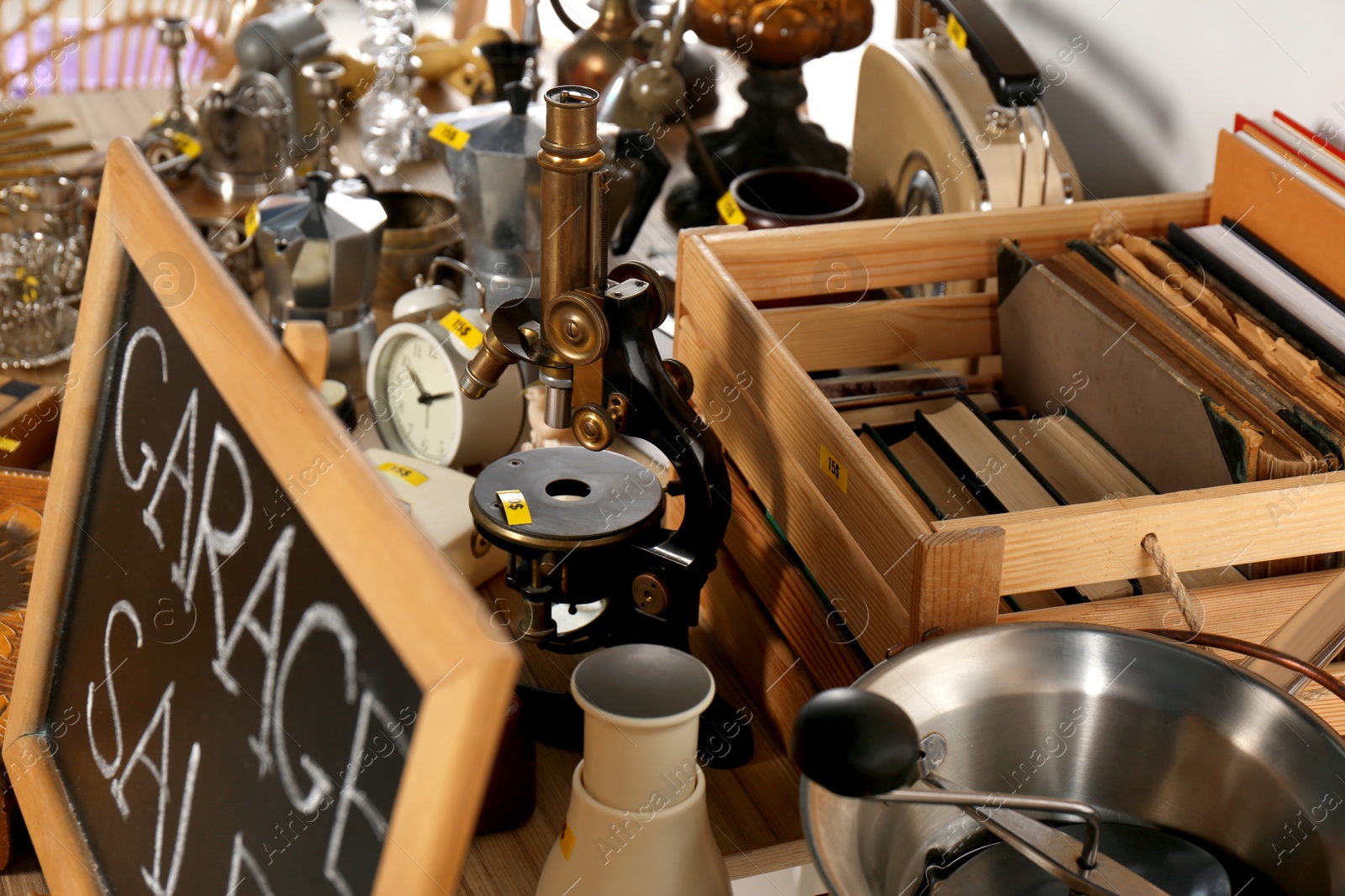 Photo of Sign Garage Sale written on blackboard near many different stuff on table