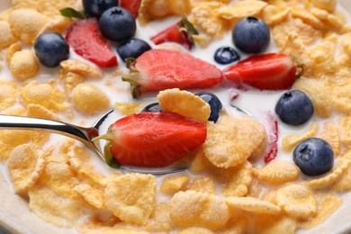 Photo of Bowl of tasty crispy corn flakes with milk and berries, closeup