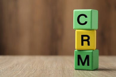 Abbreviation CRM of cubes on wooden table, space for text. Customer Relationship Management