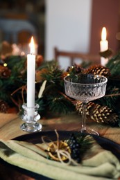 Burning candles and festive decor on wooden table. Christmas celebration