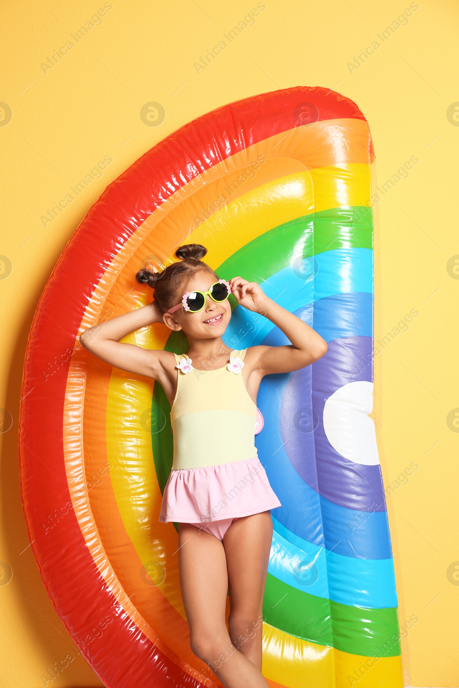 Photo of Cute little girl with inflatable mattress on color background