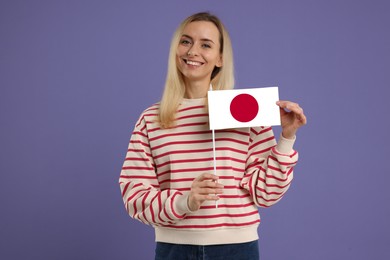 Happy young woman with flag of Japan on purple background