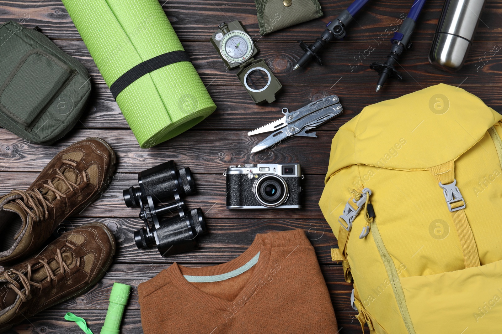 Photo of Flat lay composition with backpack and other camping equipment for tourism on wooden background