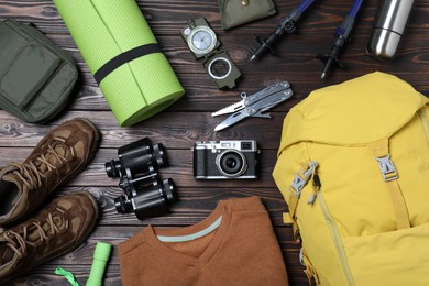 Photo of Flat lay composition with backpack and other camping equipment for tourism on wooden background
