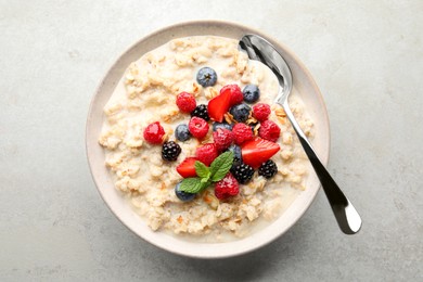 Photo of Bowloatmeal porridge served with berries on light grey table, top view