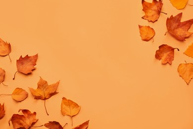 Image of Dry autumn leaves on light orange background, flat lay. Space for text