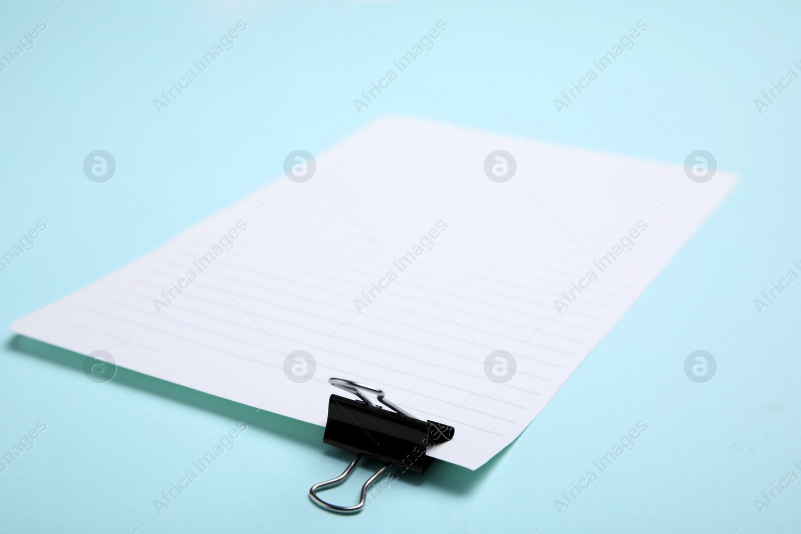 Photo of Sheet of paper with clip on light blue background