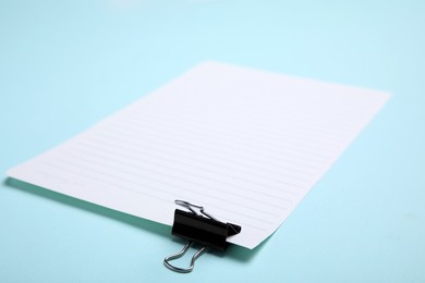 Sheet of paper with clip on light blue background