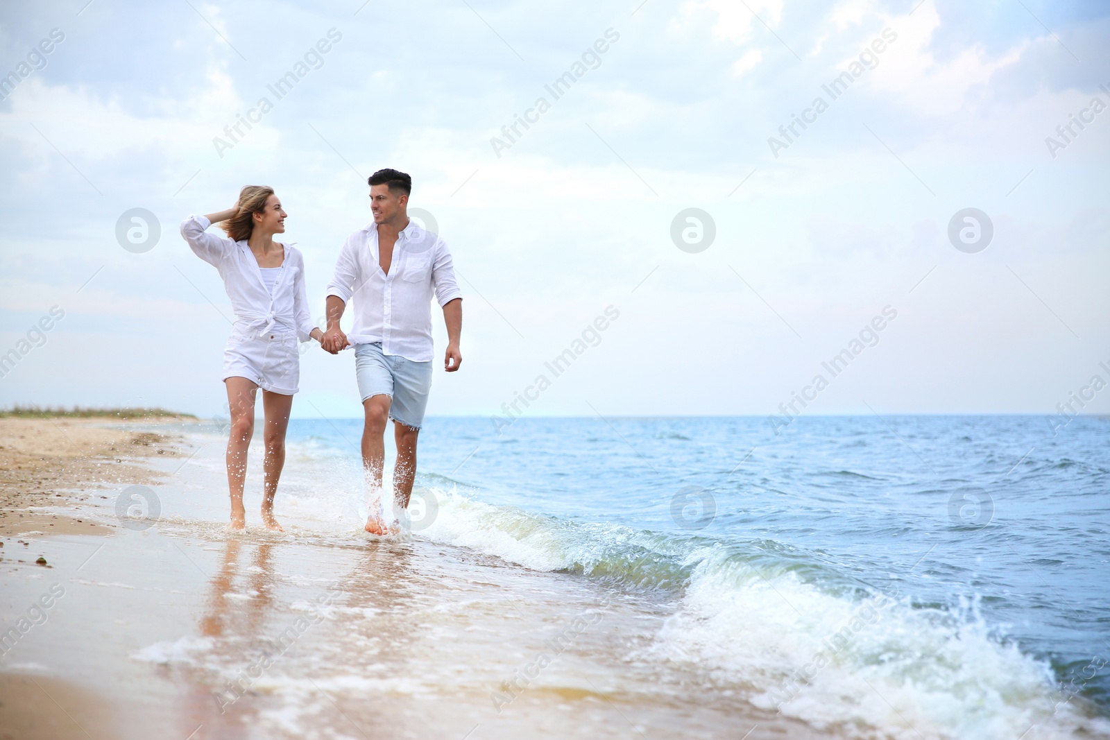 Photo of Happy couple having romantic walk on beach. Space for text