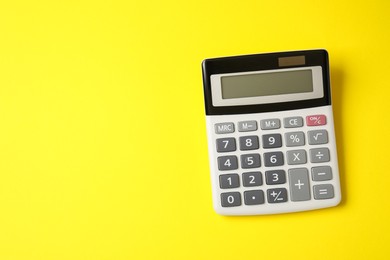 Calculator on yellow background, top view. Space for text