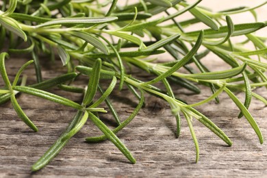 Photo of Aromatic green rosemary sprigs on wooden table, closeup