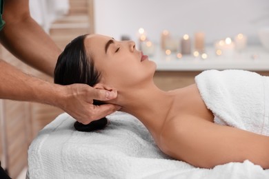 Photo of Woman receiving professional neck massage on couch in spa salon