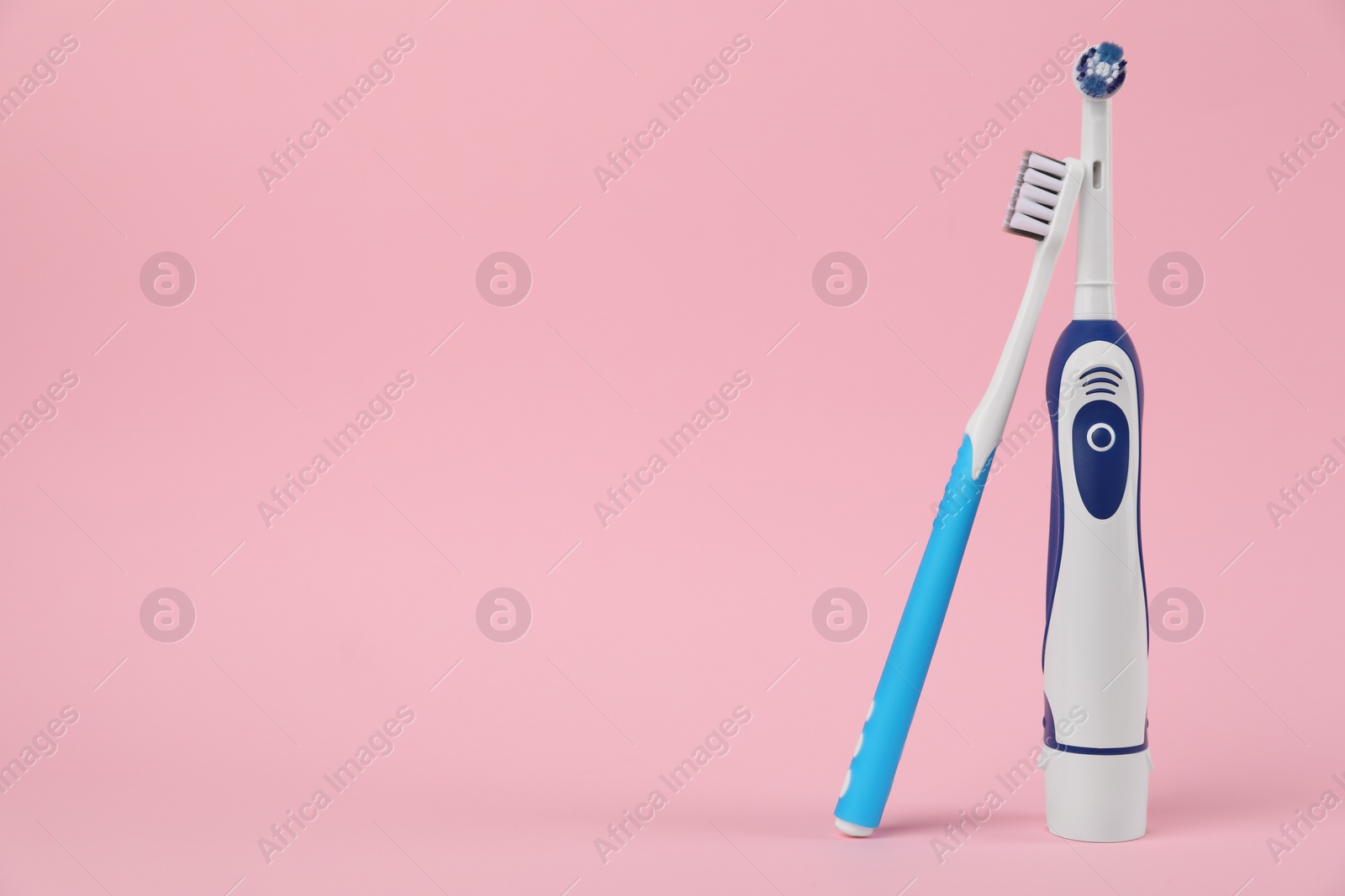 Photo of Electric toothbrushes on pink background, space for text