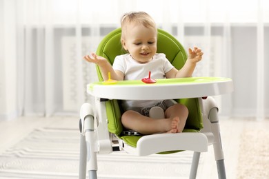 Photo of Children toys. Cute little boy playing with spinning tops in high chair at home