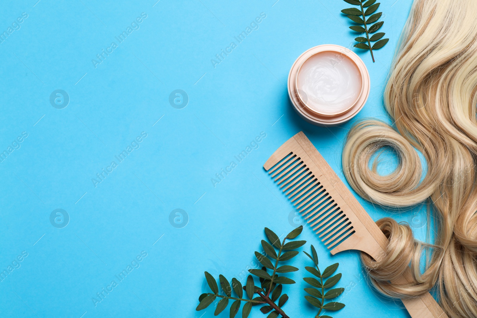 Photo of Flat lay composition with lock of healthy blond hair on light blue background. Space for text
