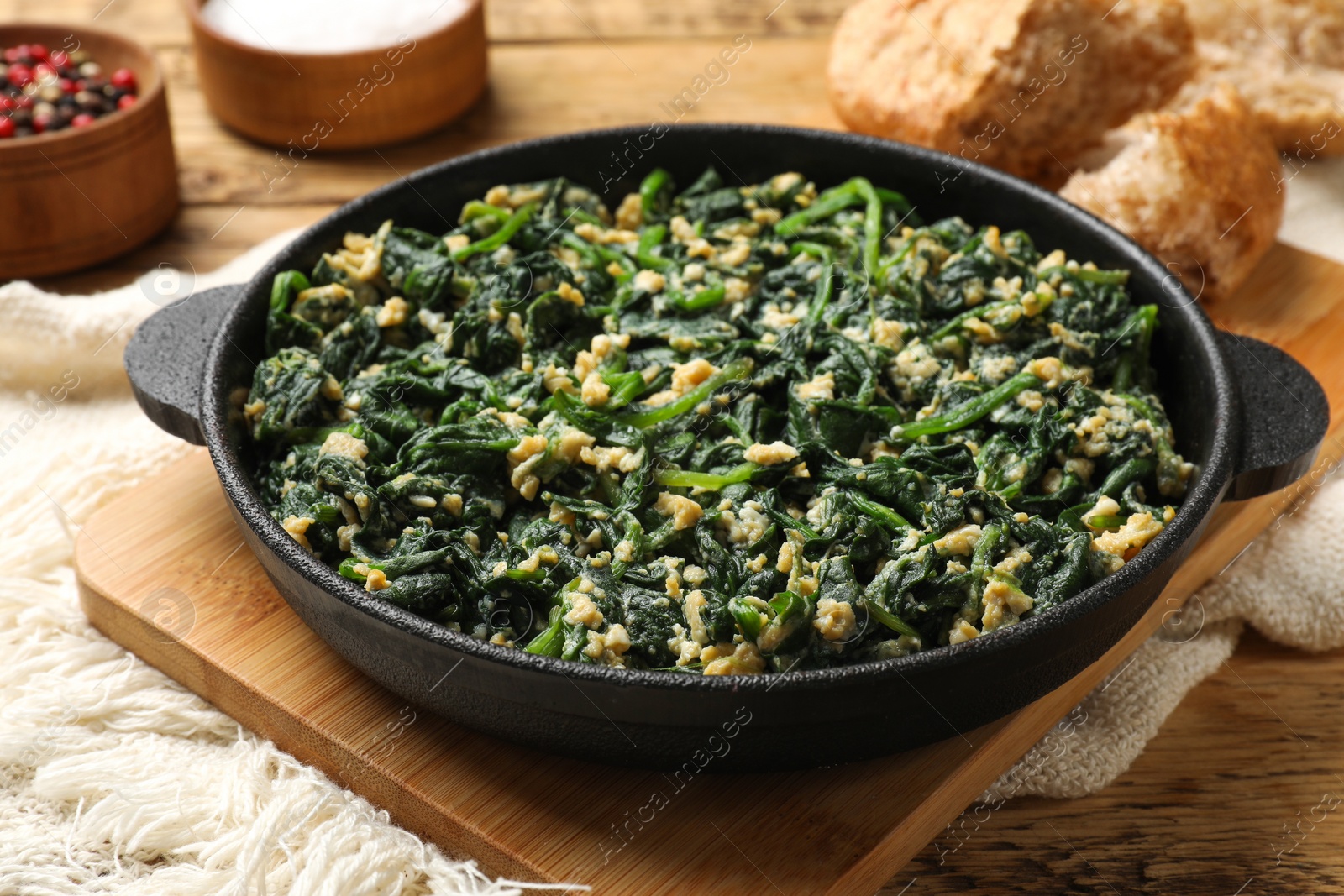 Photo of Tasty spinach dip with eggs in dish served on wooden table, closeup