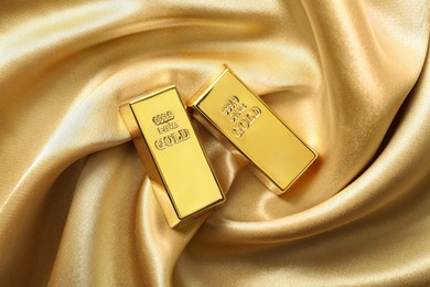 Gold bars on shiny silk fabric, flat lay