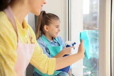 Photo of Mother and daughter wiping window at home