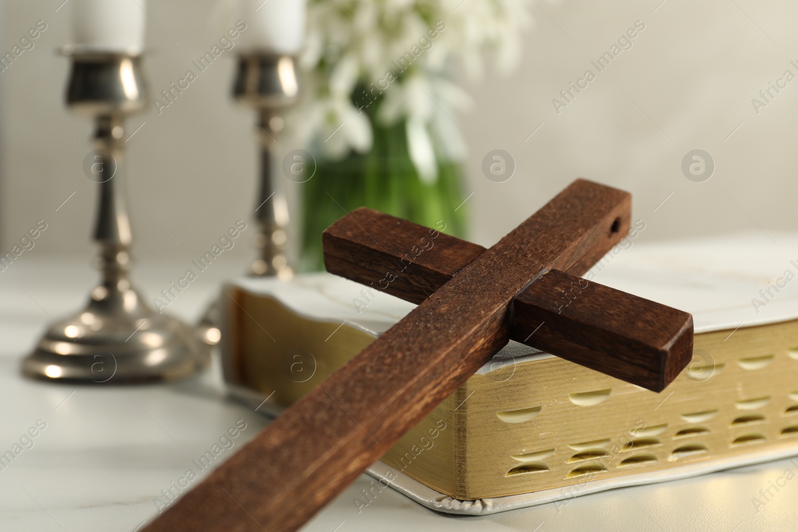 Photo of Wooden cross and Bible on white table, closeup