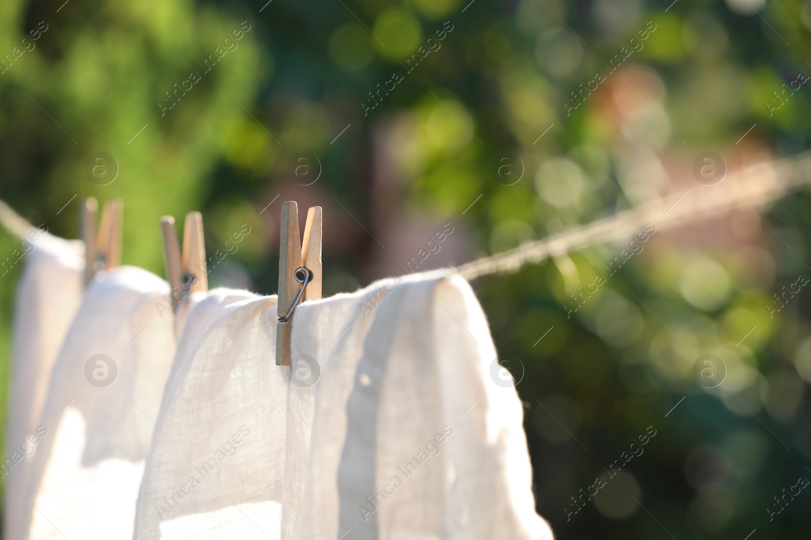 Photo of Washing line with drying shirt against blurred background, focus on clothespin