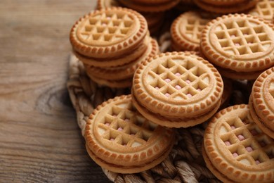 Photo of Tasty sandwich cookies with cream on wooden table, closeup. Space for text