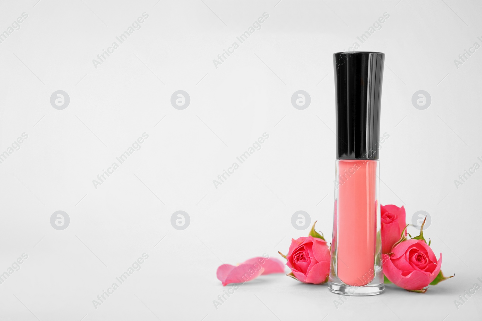 Photo of Lip gloss and flowers on light background