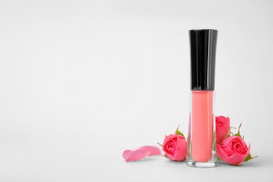 Lip gloss and flowers on light background