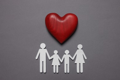 Photo of Paper family figures and red wooden heart on grey background, flat lay. Insurance concept