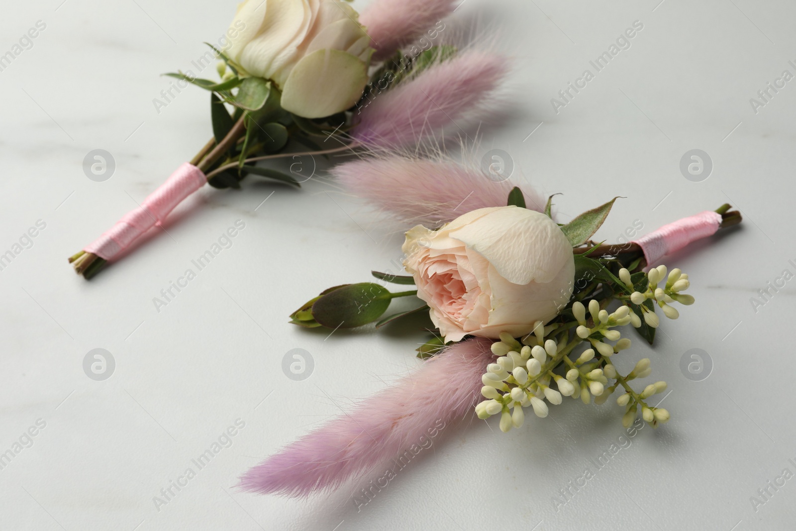 Photo of Small stylish boutonnieres on white marble table