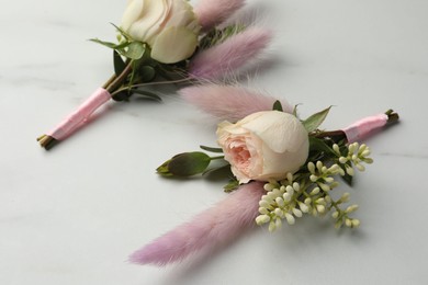 Photo of Small stylish boutonnieres on white marble table