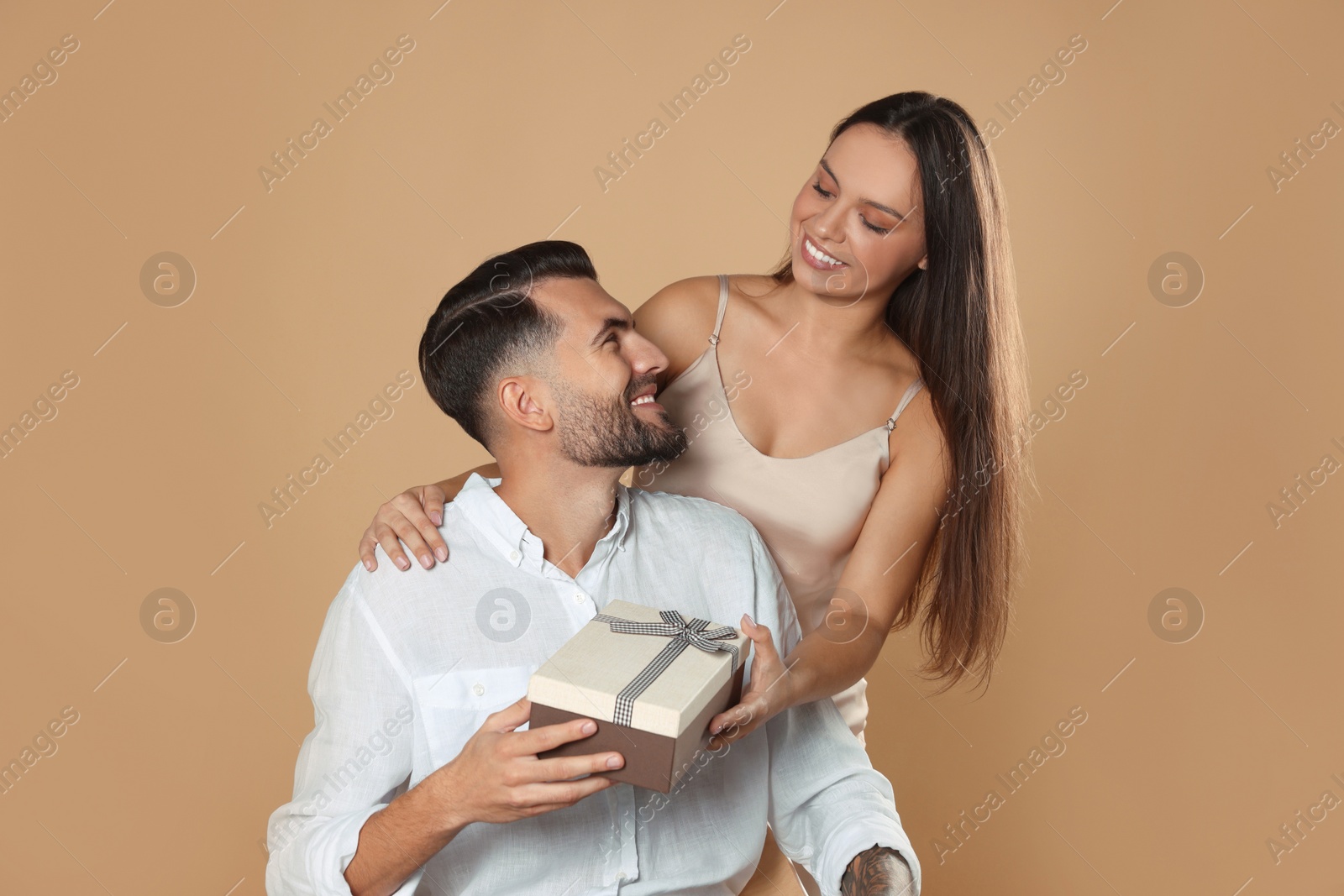 Photo of Lovely couple with gift on beige background