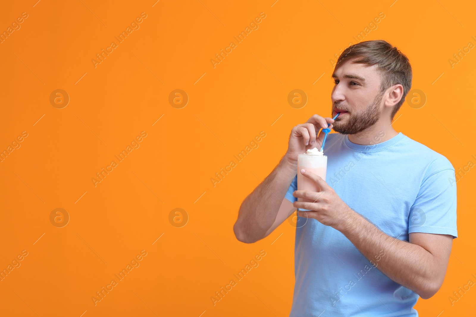 Photo of Young man with glass of delicious milk shake on color background