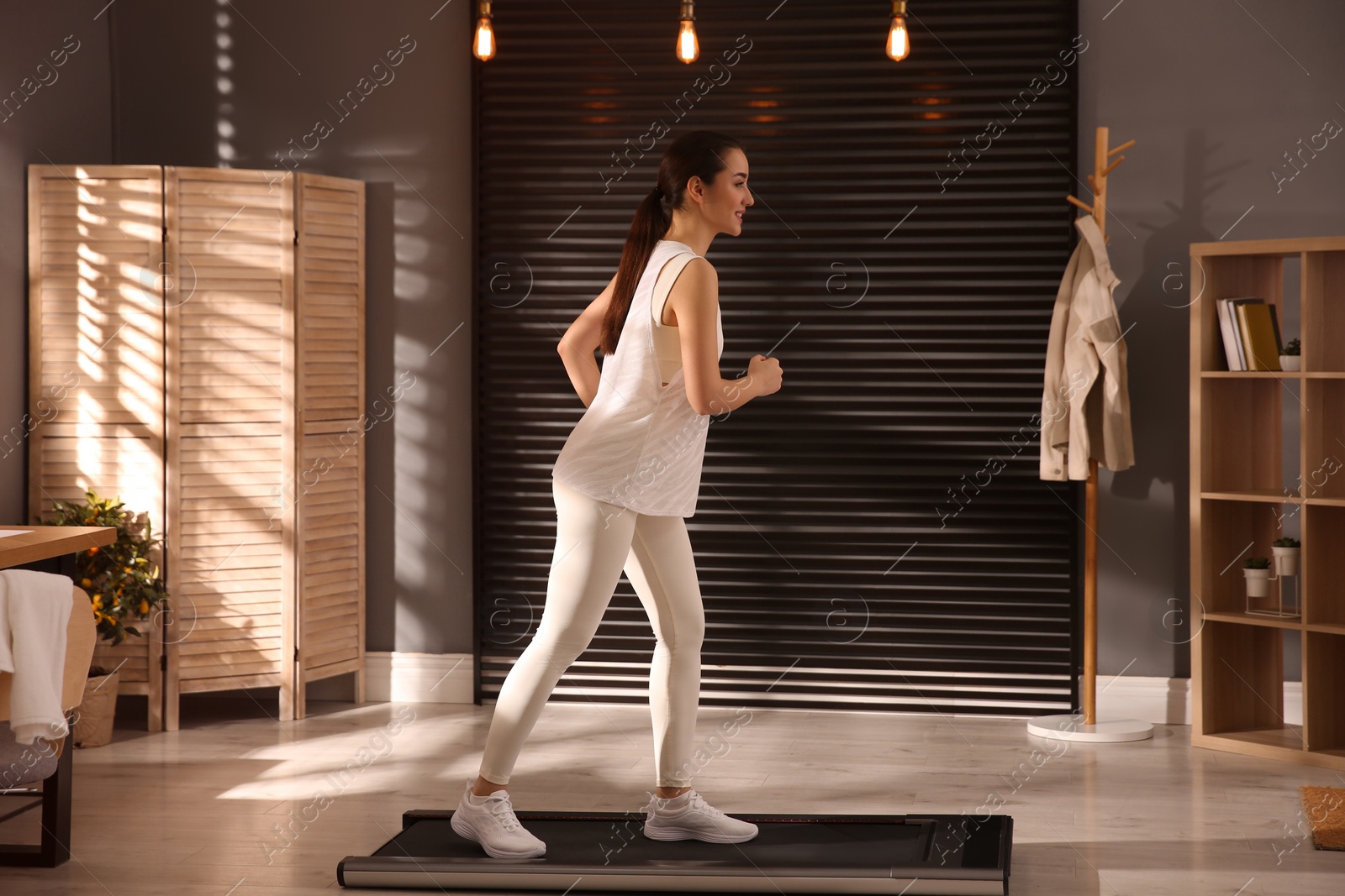 Photo of Sporty woman training on walking treadmill at home