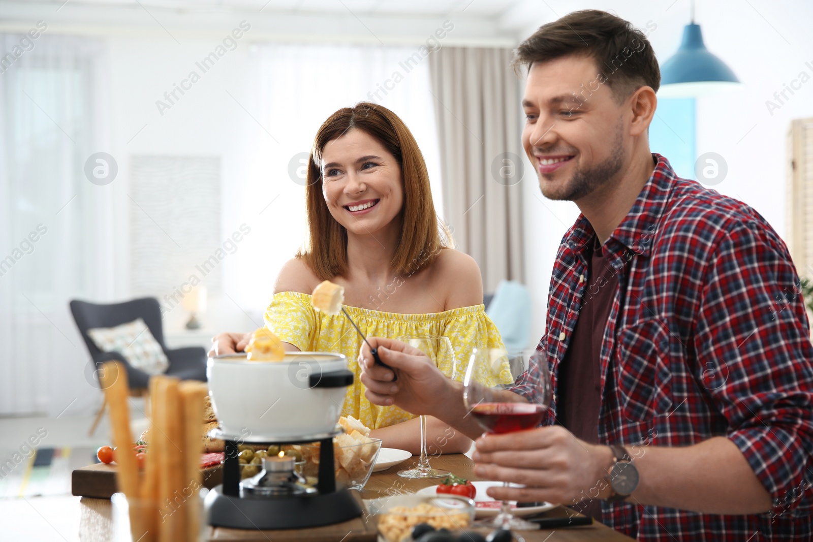 Photo of Happy couple enjoying fondue dinner at home