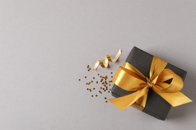 Photo of Beautifully wrapped gift box and confetti on grey background, flat lay. Space for text