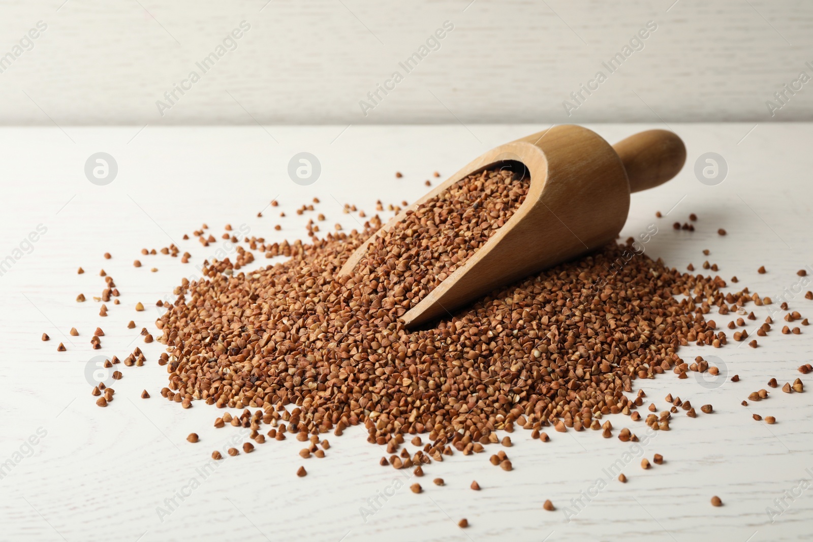 Photo of Uncooked buckwheat grains on white wooden table