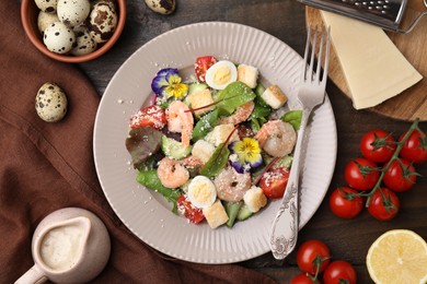 Photo of Delicious Caesar salad with shrimps and ingredients on wooden table, flat lay