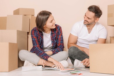 Happy couple surrounded by moving boxes choosing colors in new apartment