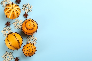 Photo of Flat lay composition with pomander balls made of fresh tangerines and oranges on light blue background. Space for text