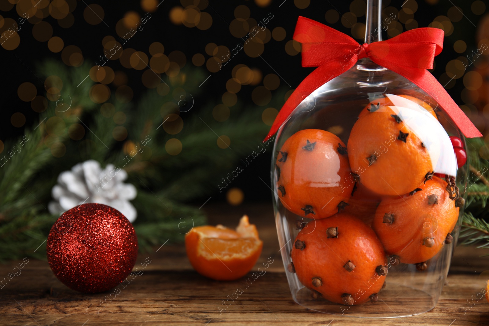 Photo of Christmas composition with tangerine pomander balls in wineglass on wooden table. Space for text